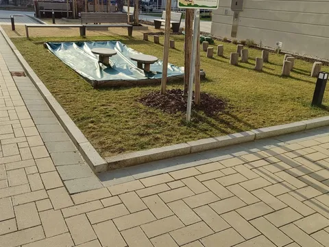 Gepflegte Rasenfläche mit Sandkasten und Sitzgelegenheiten auf einem Spielplatz einer Wohnanlage.