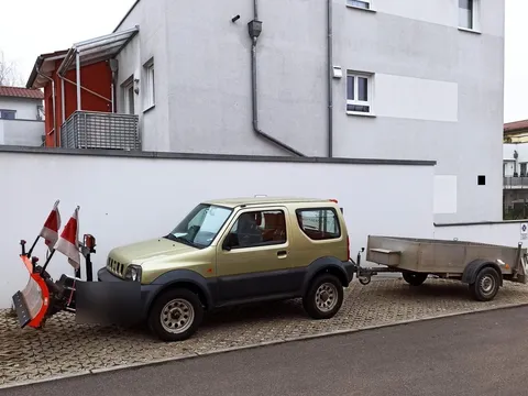 Unser Geländewagen mit montiertem Schneeschild und Anhänger, einsatzbereit vor einem Wohngebäude.